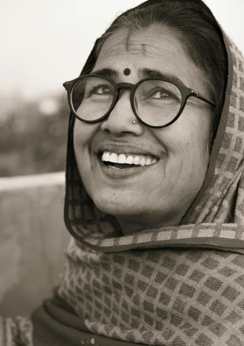 A woman wearing a scarf and glasses smiling
