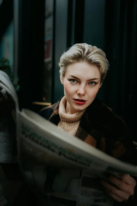 a woman is reading a newspaper outside