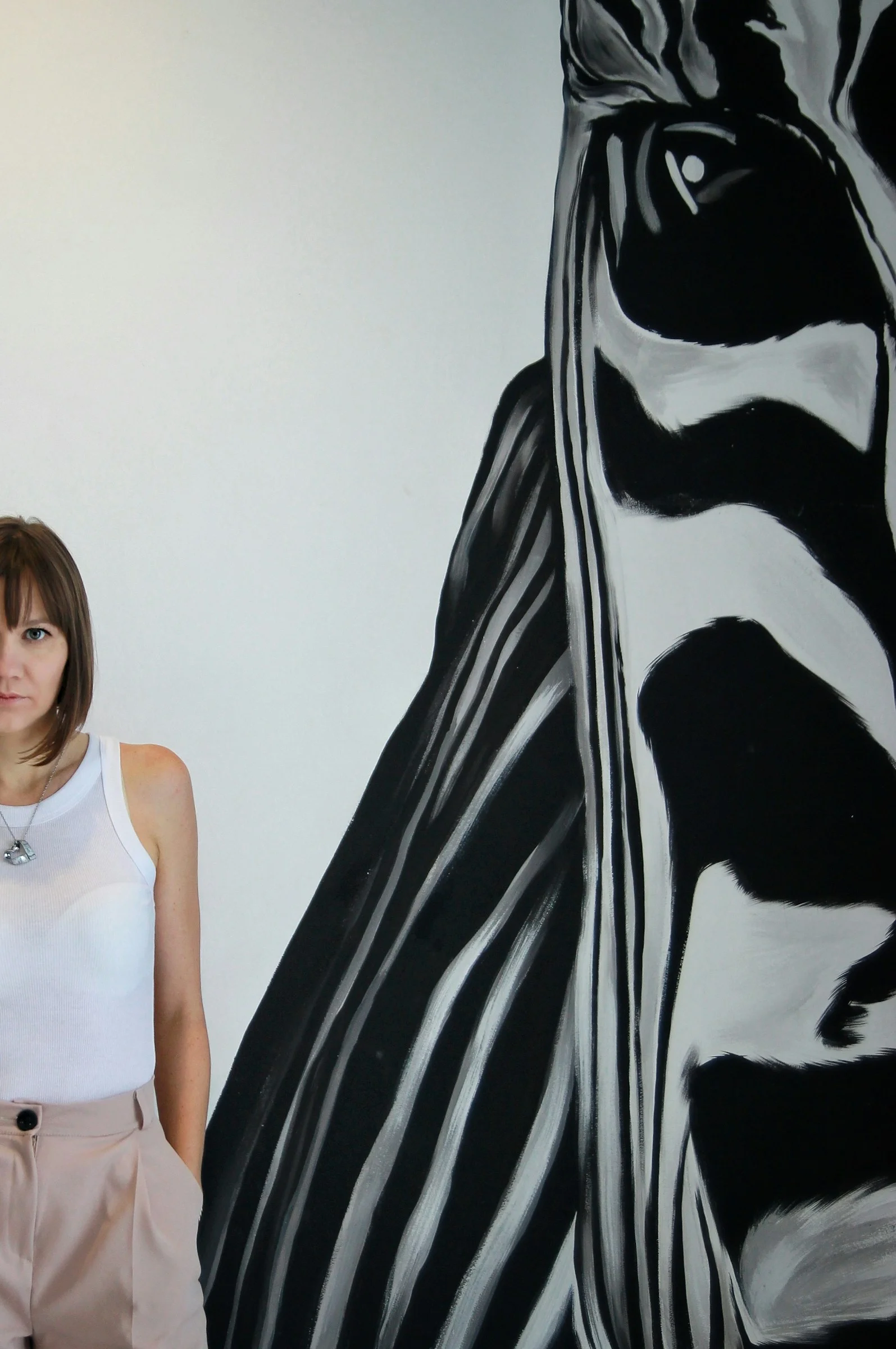 a woman standing in front of a painting of a zebra