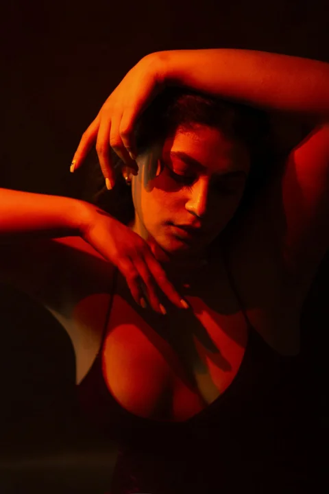 a woman in a dark room with her hand on her shoulder