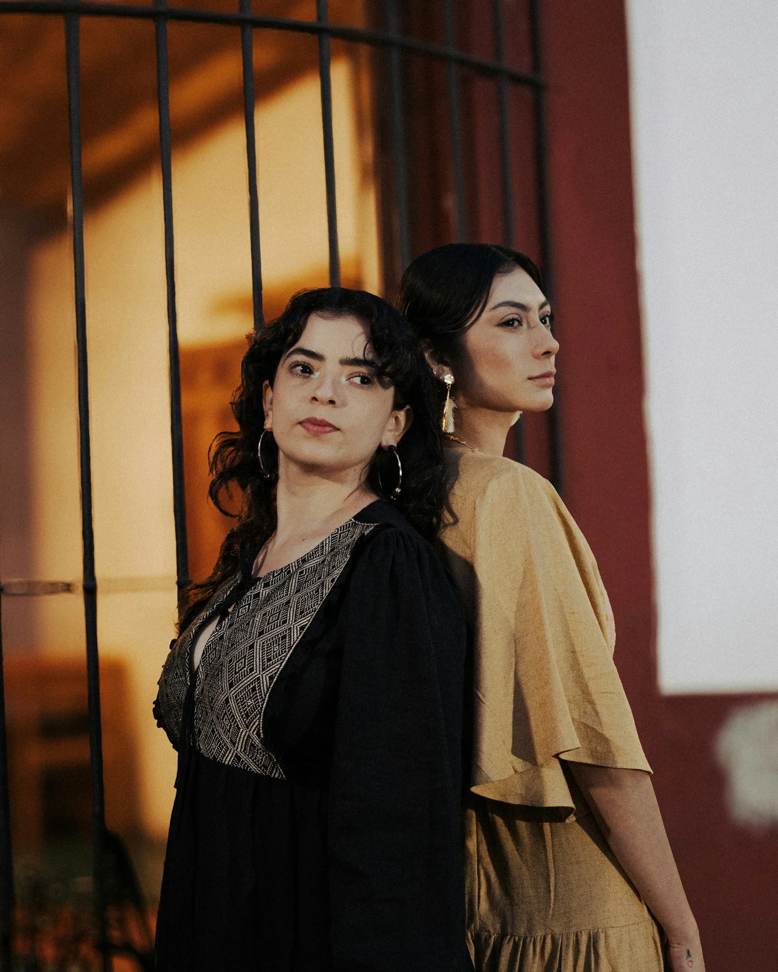 Two women stand back to back, striking a pose
