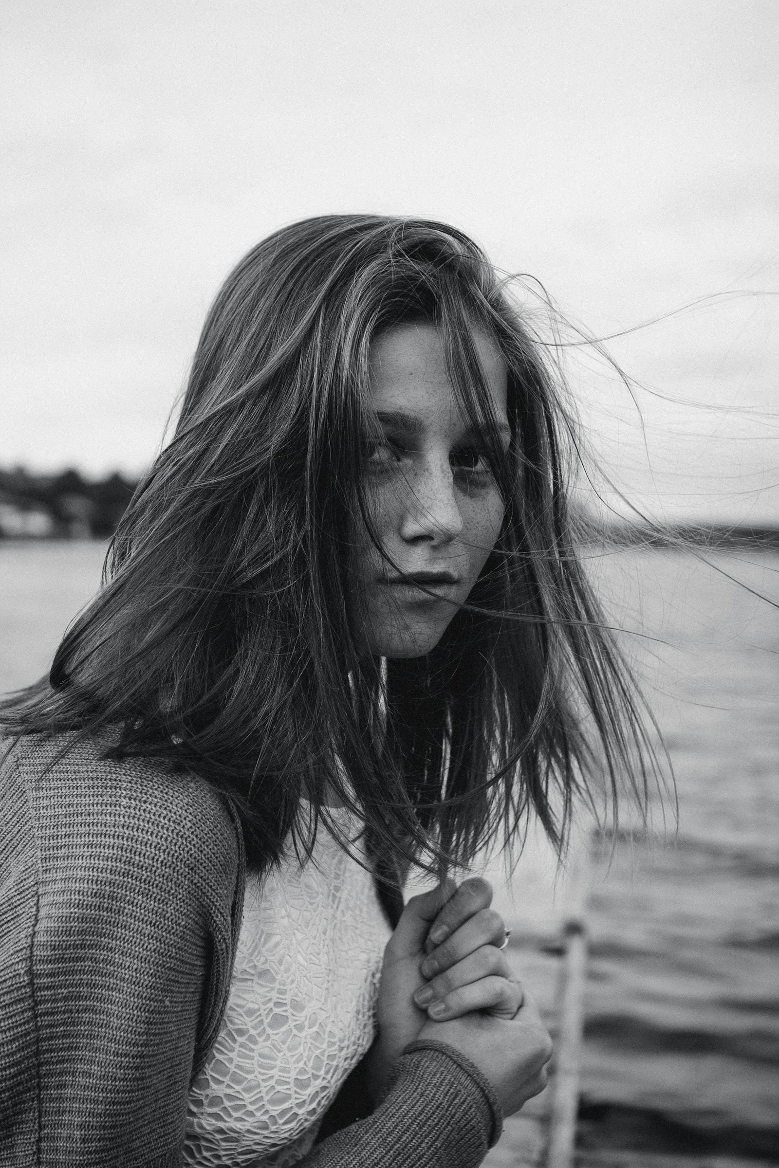 A woman with long hair standing next to a body of water