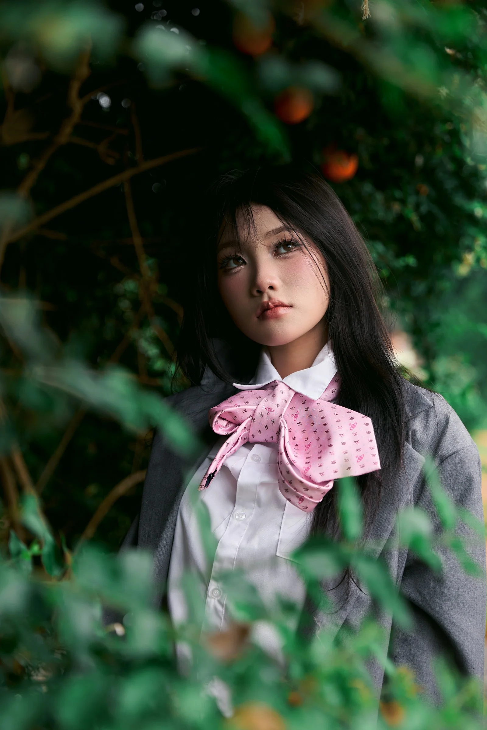 Young woman in school uniform surrounded by green foliage