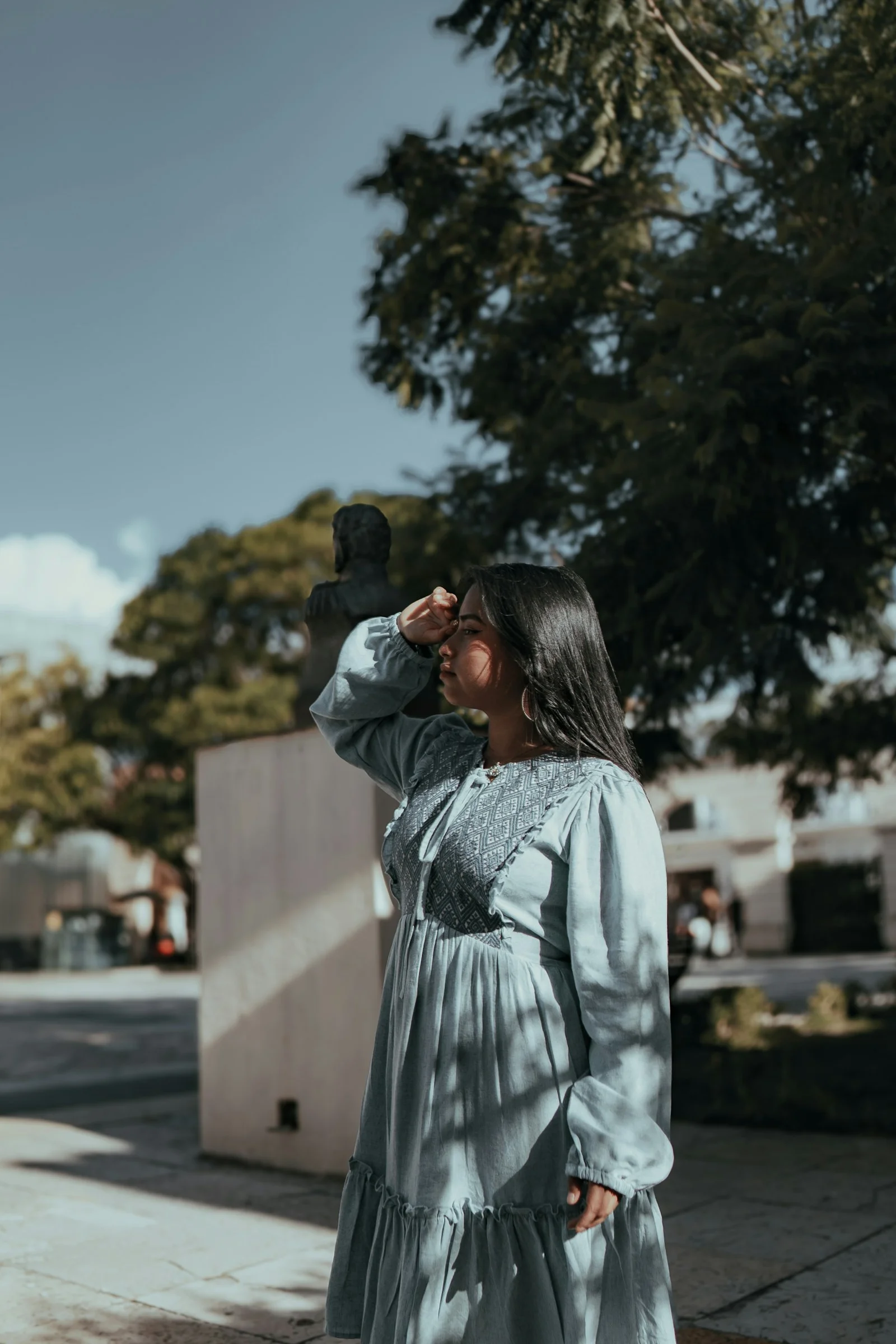 Woman shields eyes in sunny outdoor setting