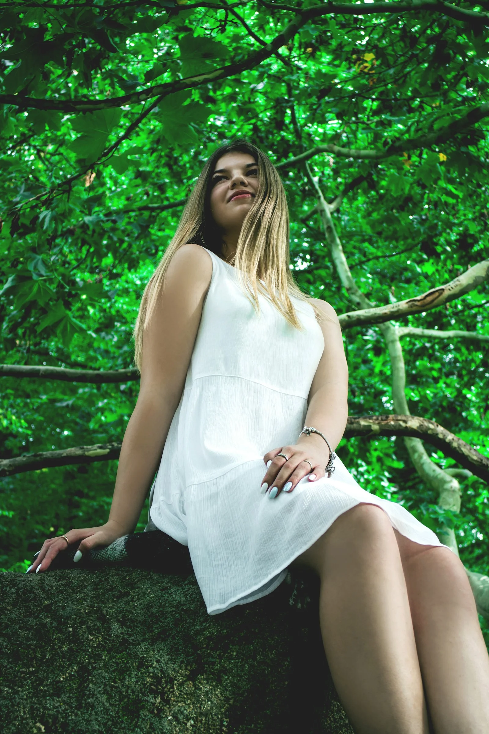 woman in white sleeveless dress sitting on tree branch