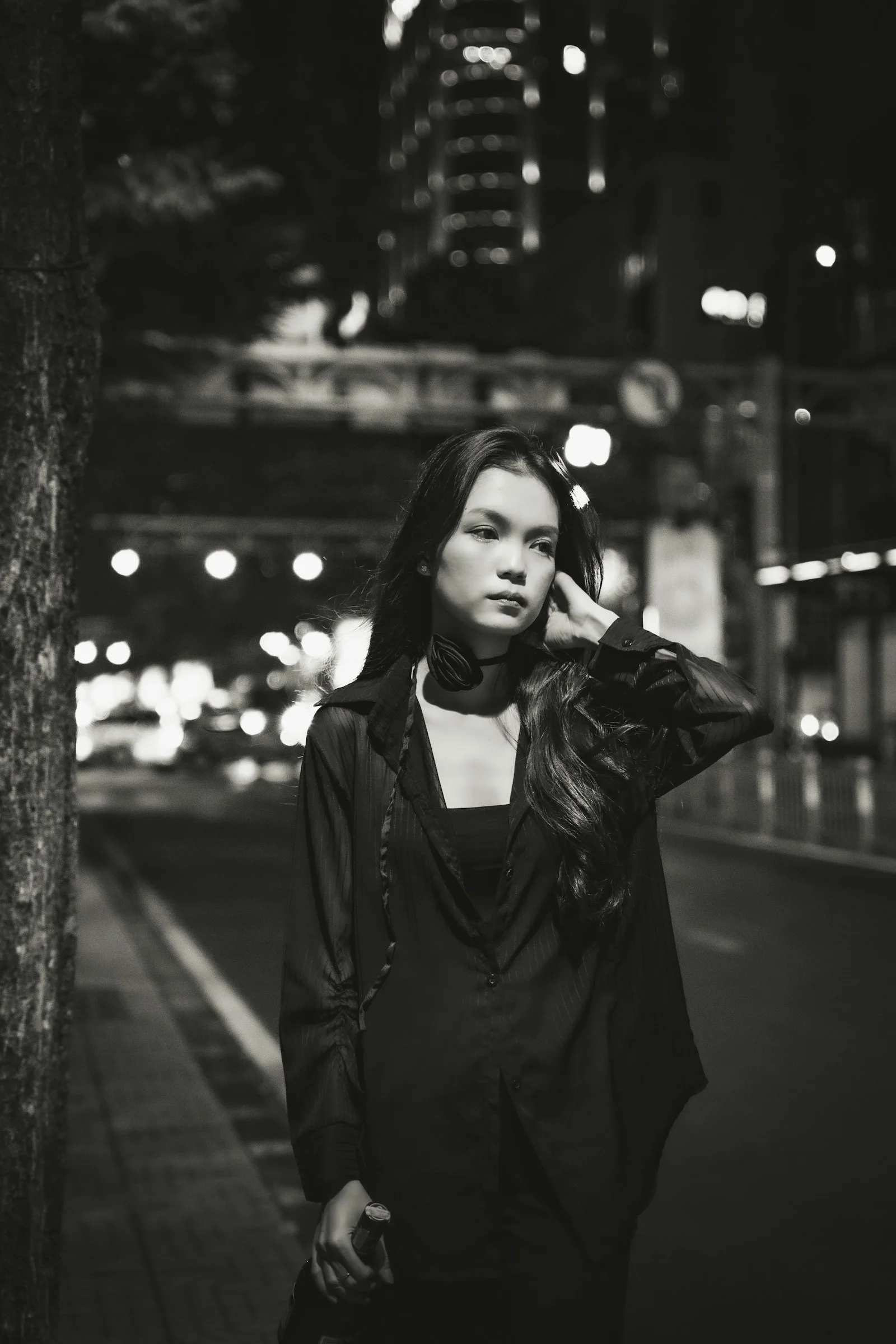 a woman standing next to a tree on a street