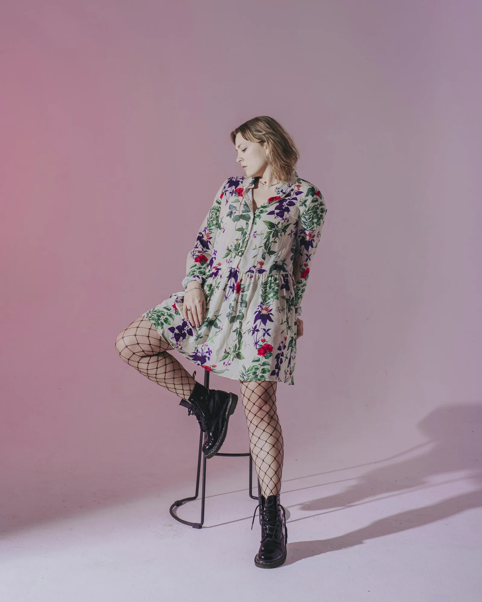 白・赤・緑の花柄の長袖シャツを着て立っている女性