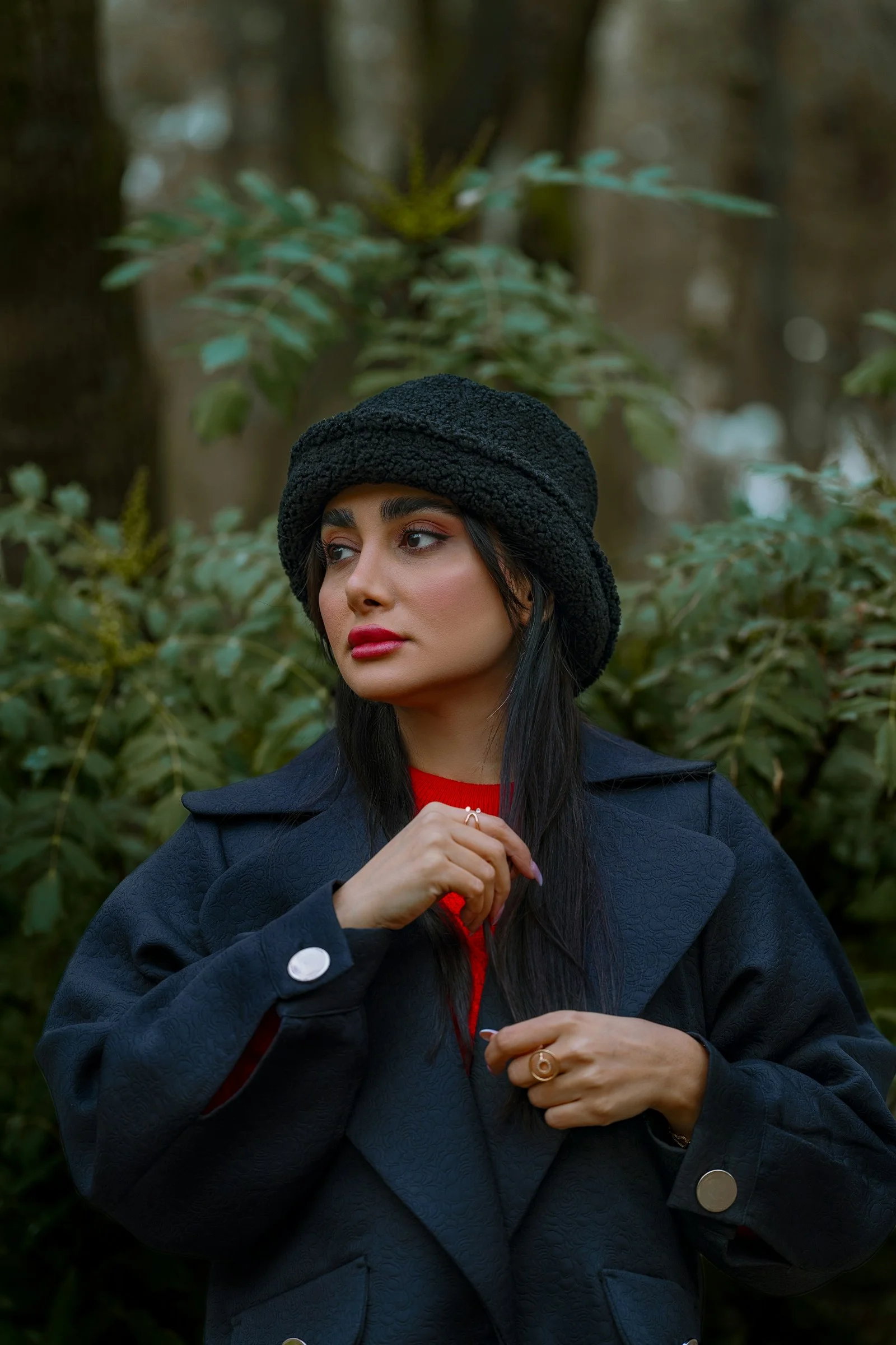 A woman poses in a black coat and hat