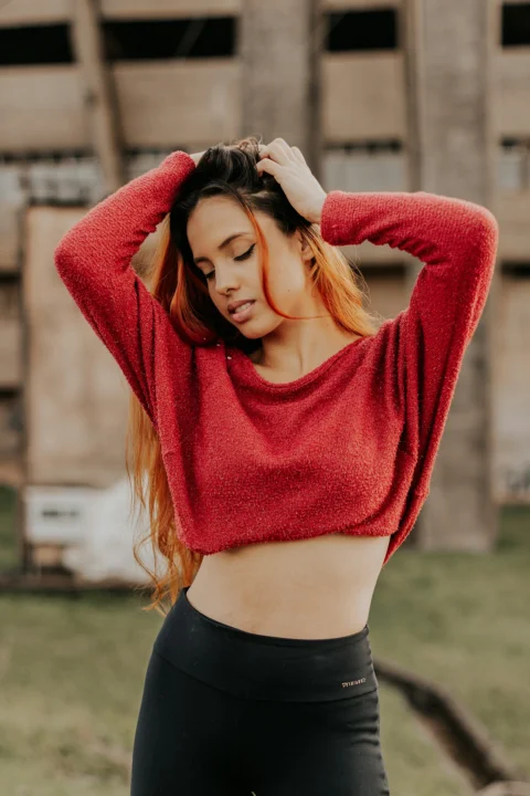 woman in red sweater standing on green grass field during daytime