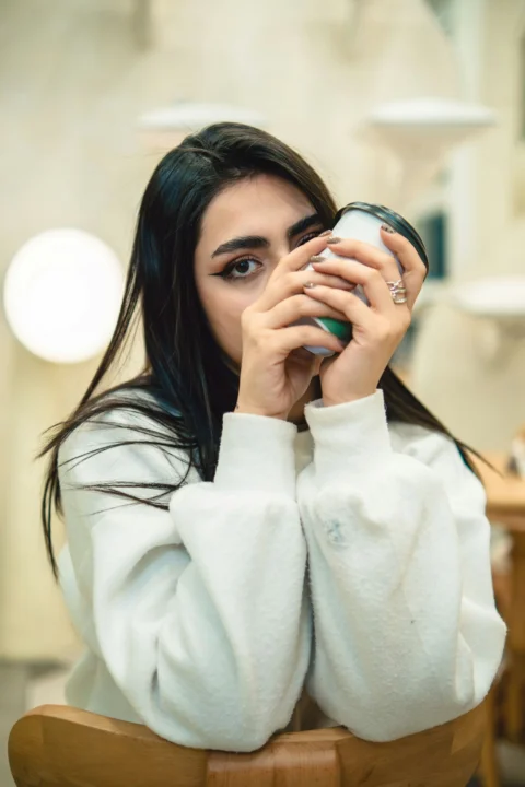 Young woman holding a coffee cup to her face