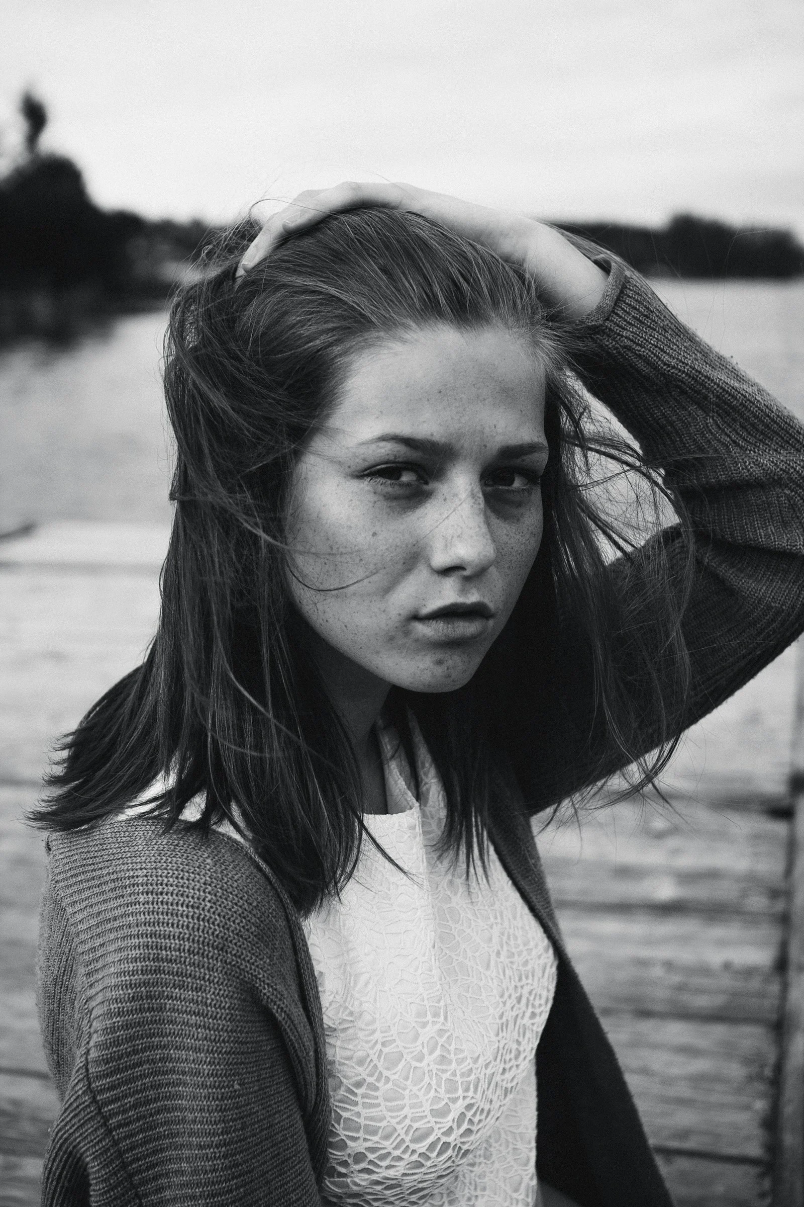 A woman standing on a dock with her hair blowing in the wind