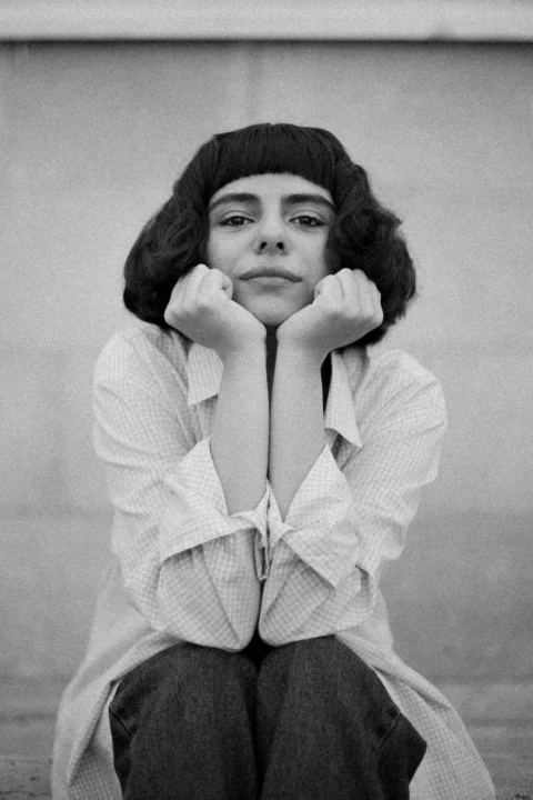 Young woman poses with her hands on her chin