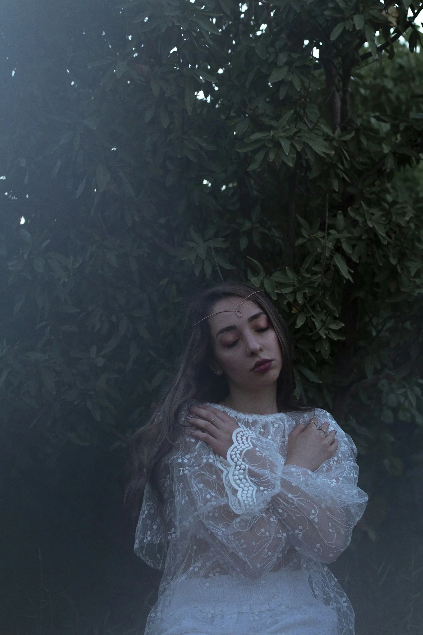 a woman in a white dress standing in front of a tree