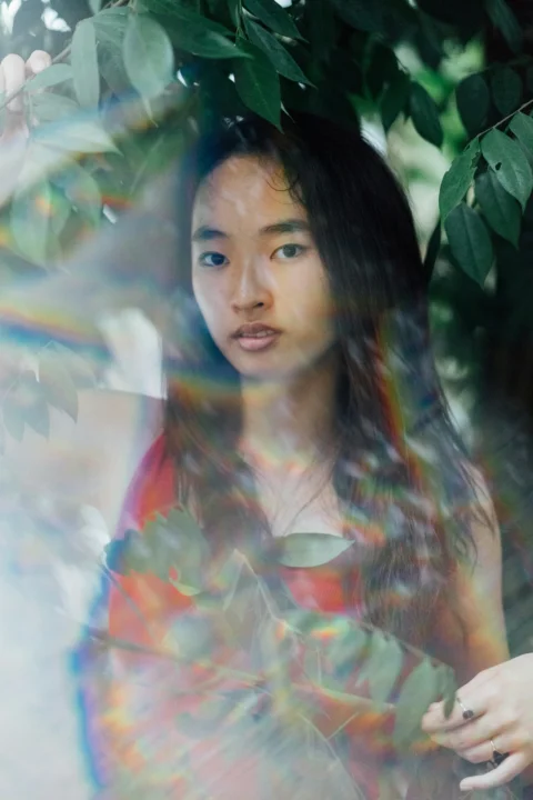 站在绿叶植物旁的女性