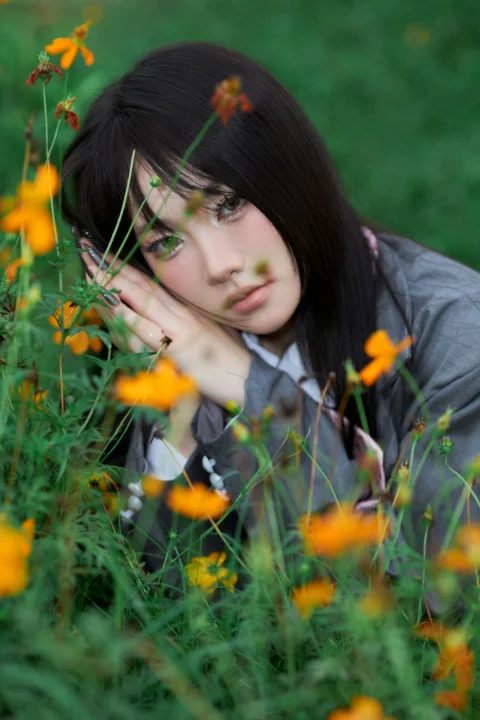 Young woman resting gently amidst vibrant orange cosmos flowers