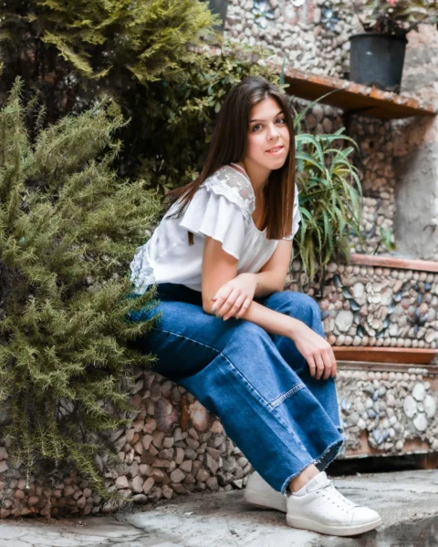 a woman sitting on a stone step next to a plant