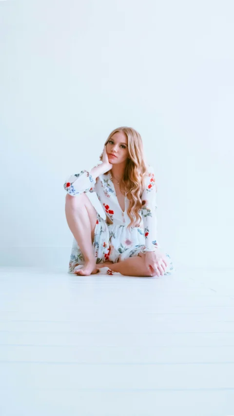 woman in white and red floral dress sitting on white floor