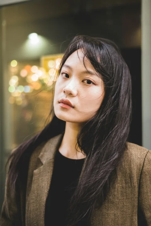 一位长黑发的女子站在建筑物前