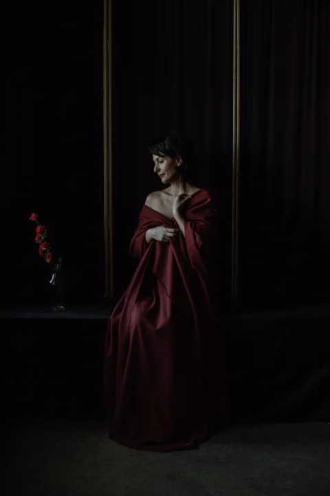 a woman in a red dress standing in a dark room