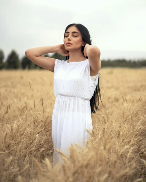 a person in a white dress standing in a field of tall grass