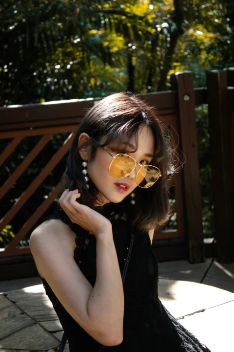 フェンスのそばに立つ黒いノースリーブトップスの女性