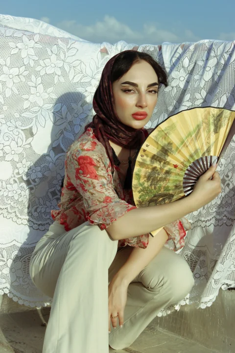 a woman in a hijab is holding a fan