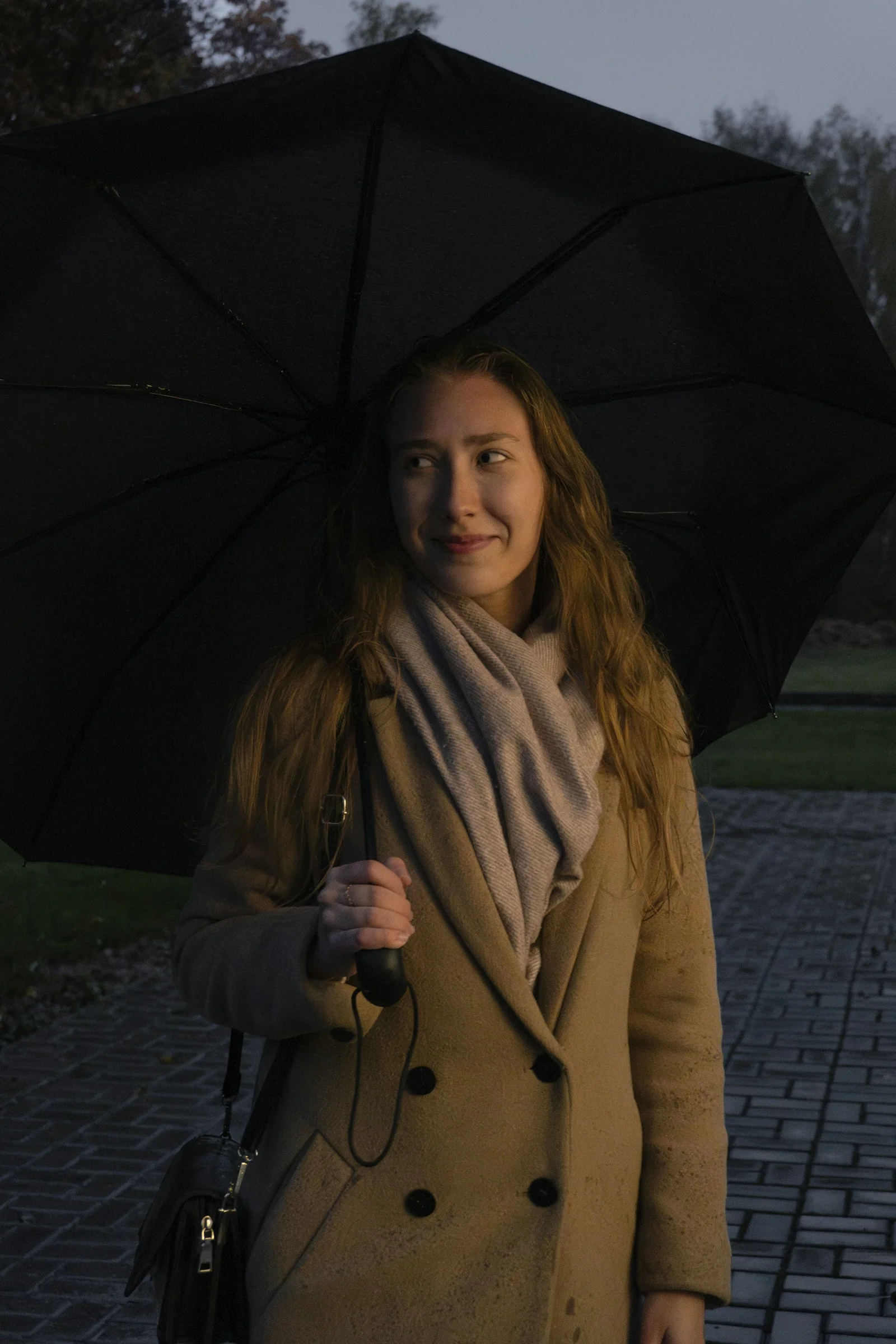 a woman holding a black umbrella on a sidewalk
