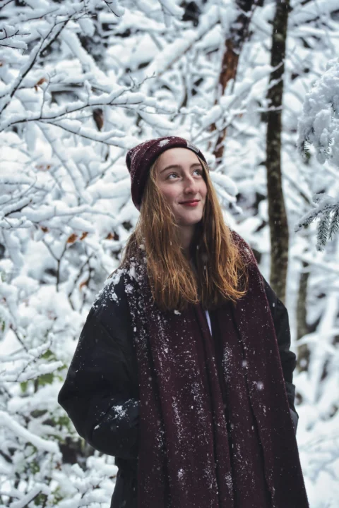 woman in black coat standing near trees during daytime