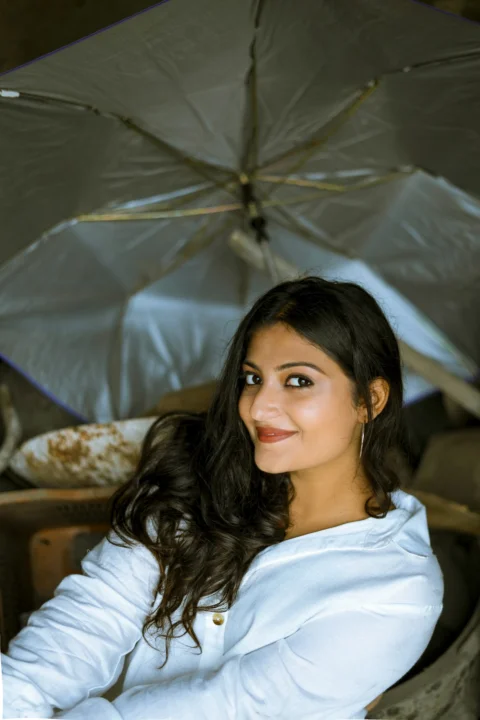 a woman sitting in a chair under an umbrella