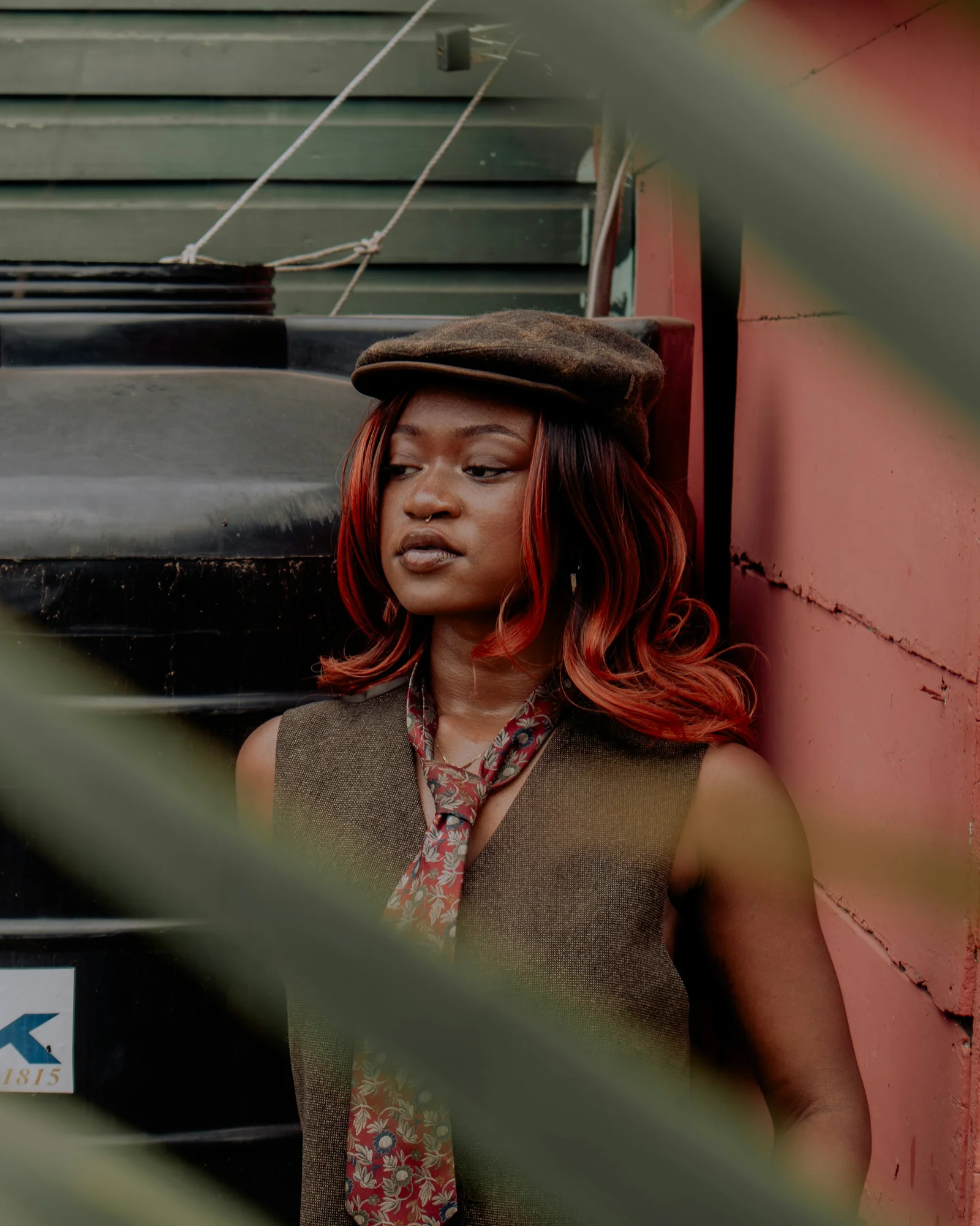 Stylish woman poses near a wall and plants