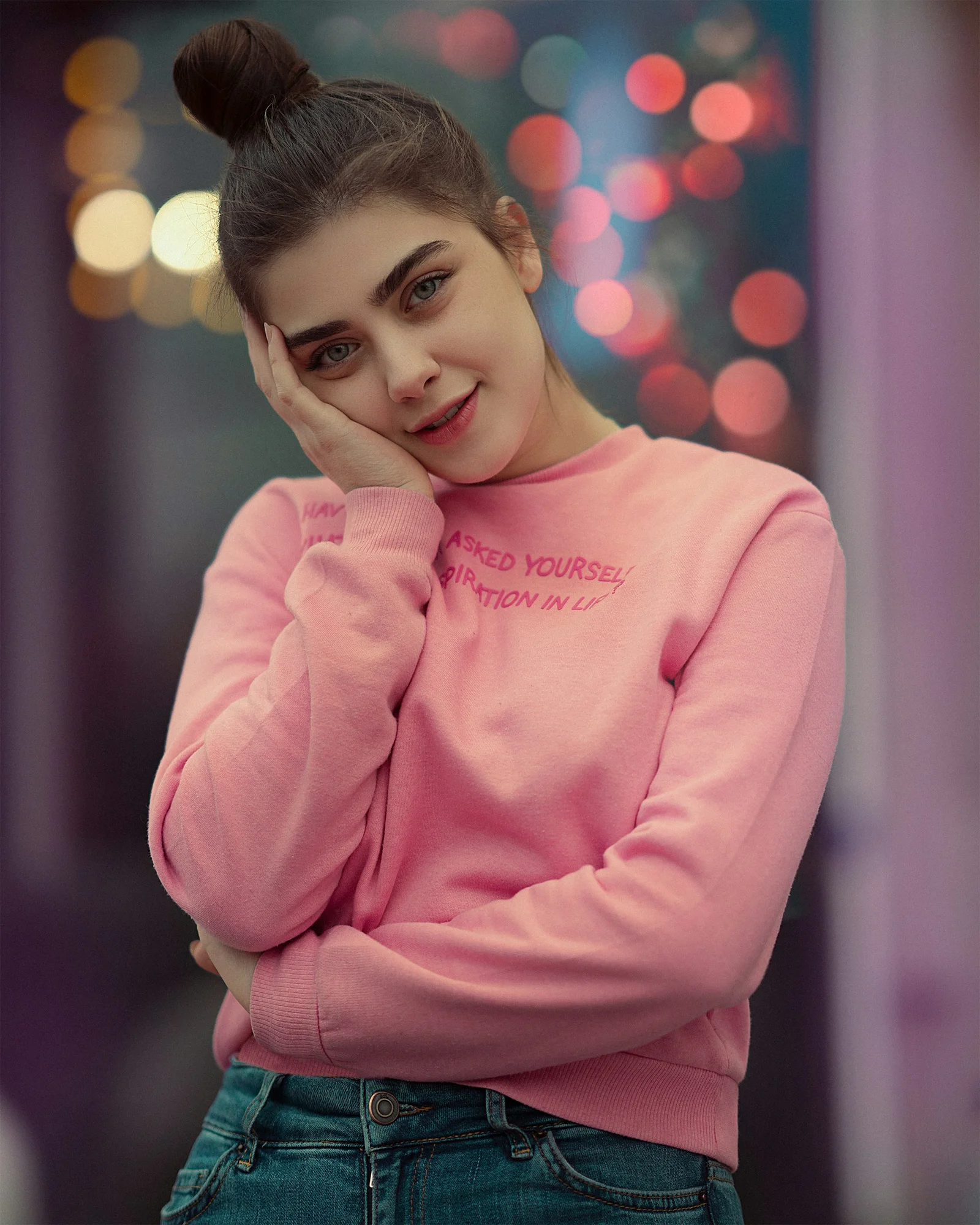 a woman with a ponytail wearing a pink sweater