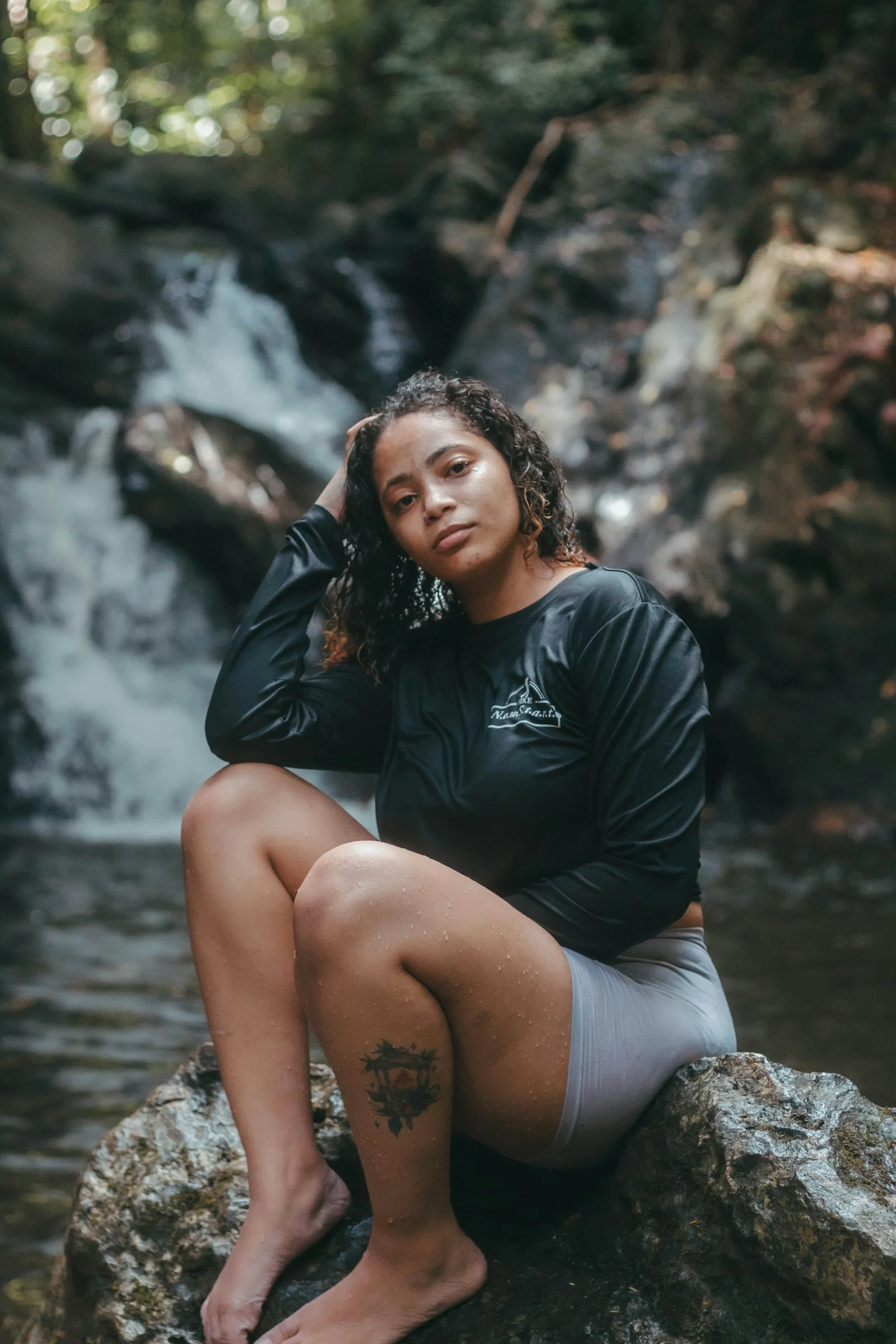 a woman sitting on top of a rock next to a river