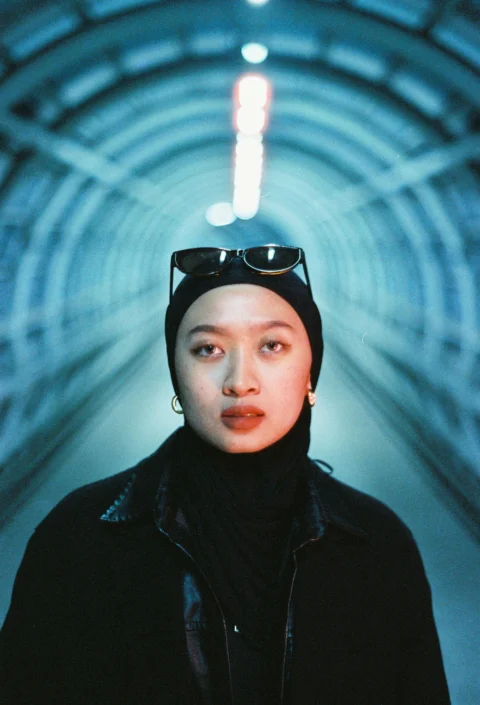 Young woman poses in a neon-lit tunnel
