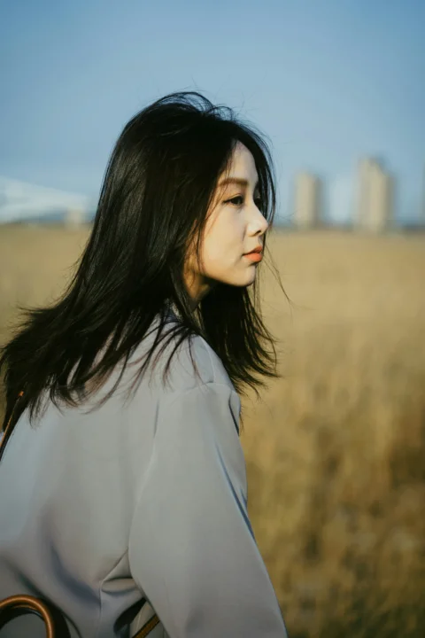 留著長髮站在田野中的女子