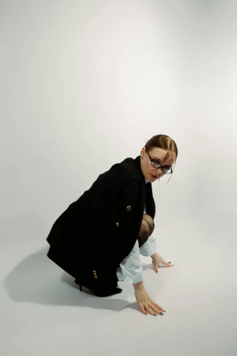 A woman squats, posing in a dramatic manner