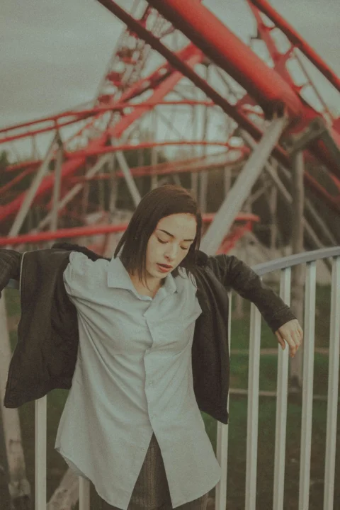 woman in gray long sleeve shirt and black pants standing near white metal fence
