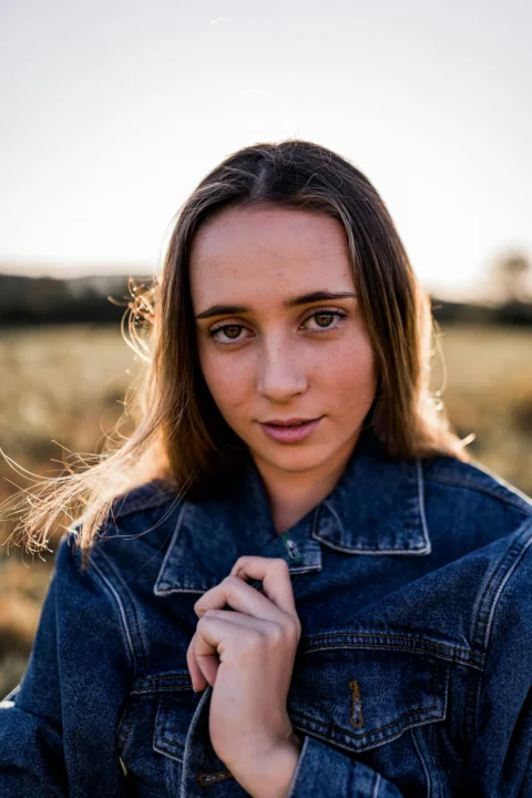a woman in a denim jacket posing for a picture