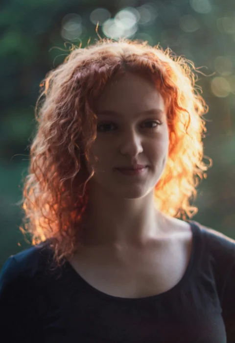 阳光下红色卷发的年轻女子