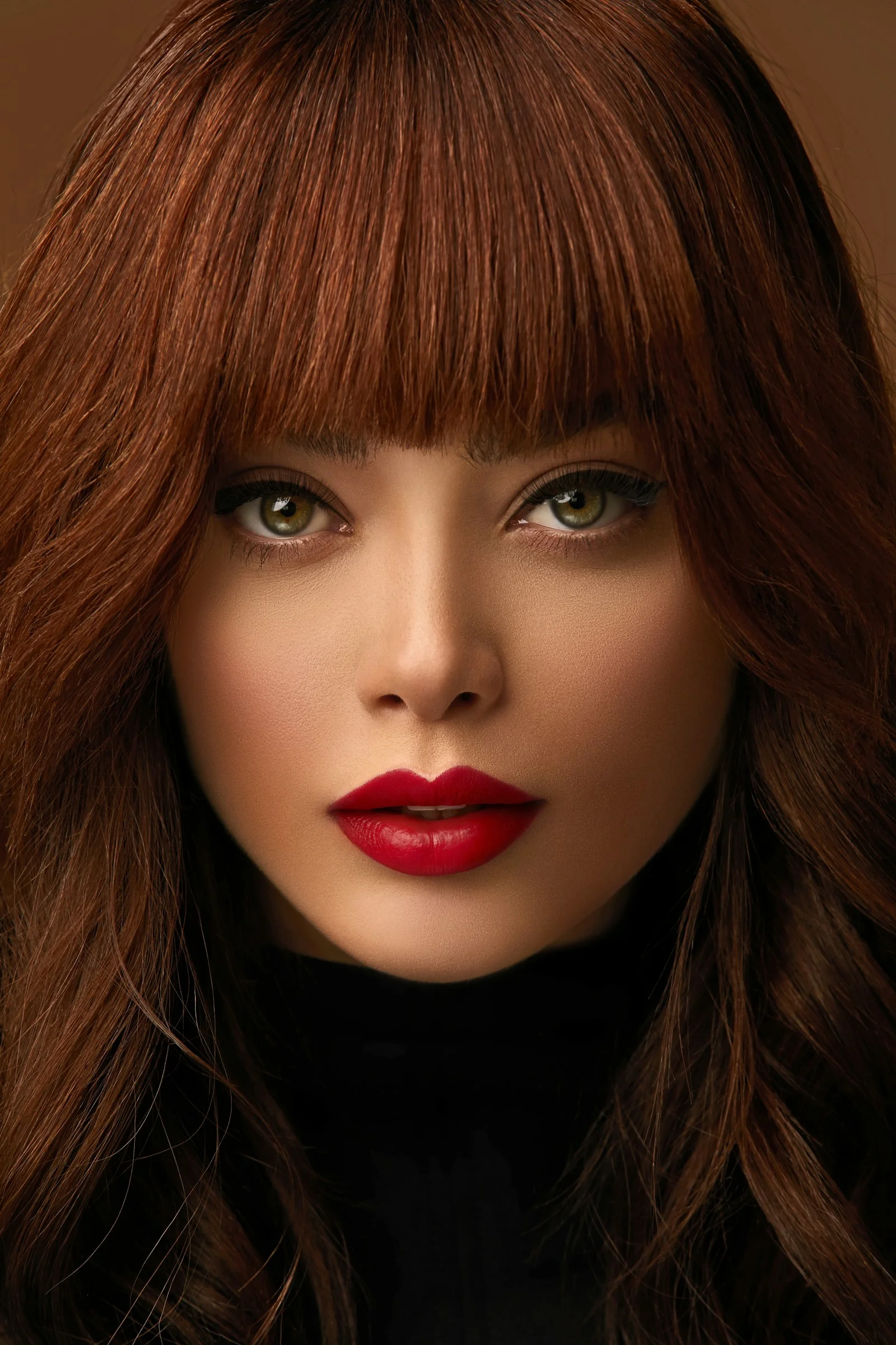 A woman with auburn hair and bangs, green eyes, and bright red lipstick