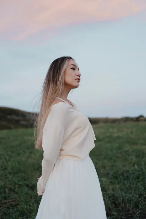 A woman in a white dress standing in a field