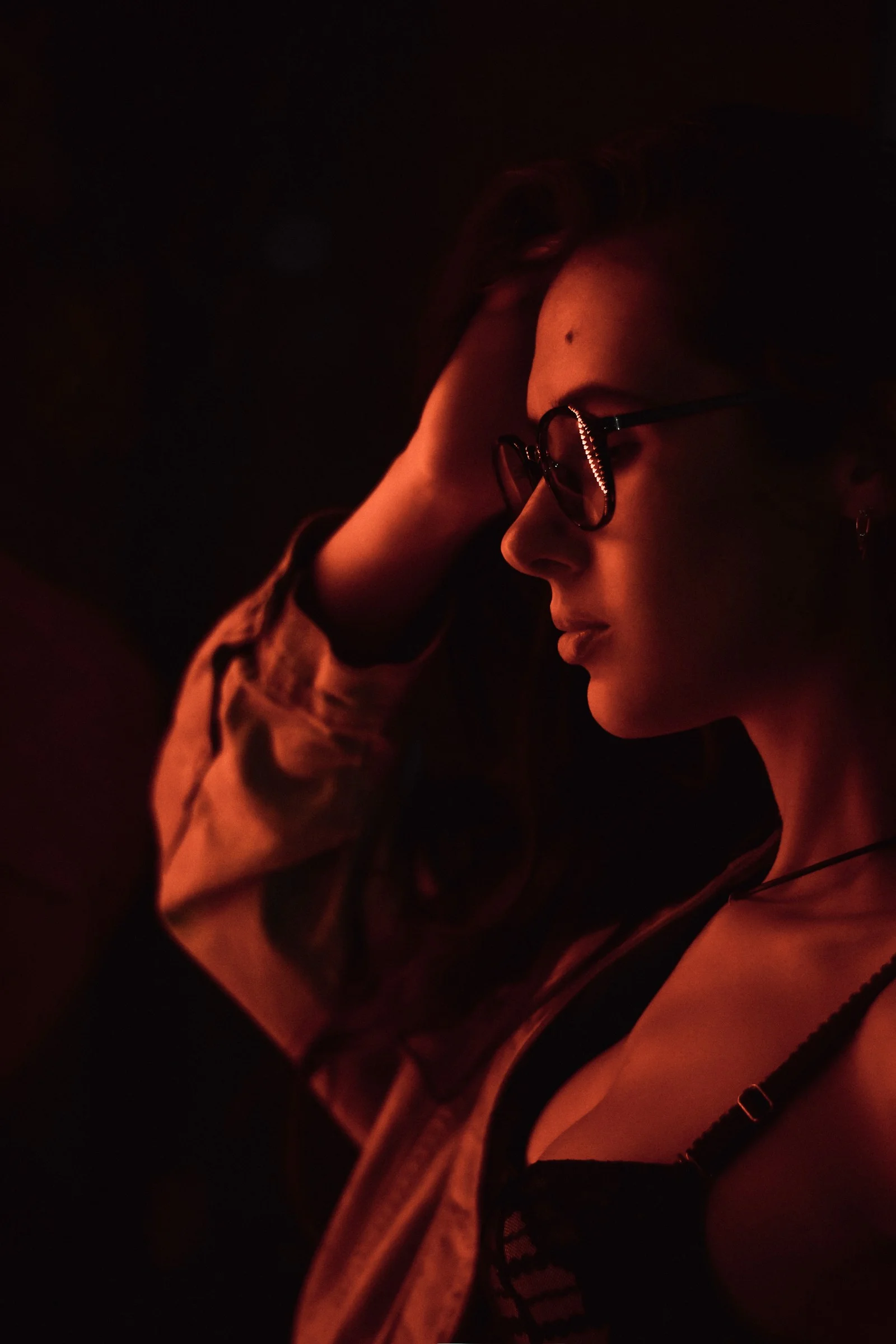 a woman in a dark room with her hand on her head