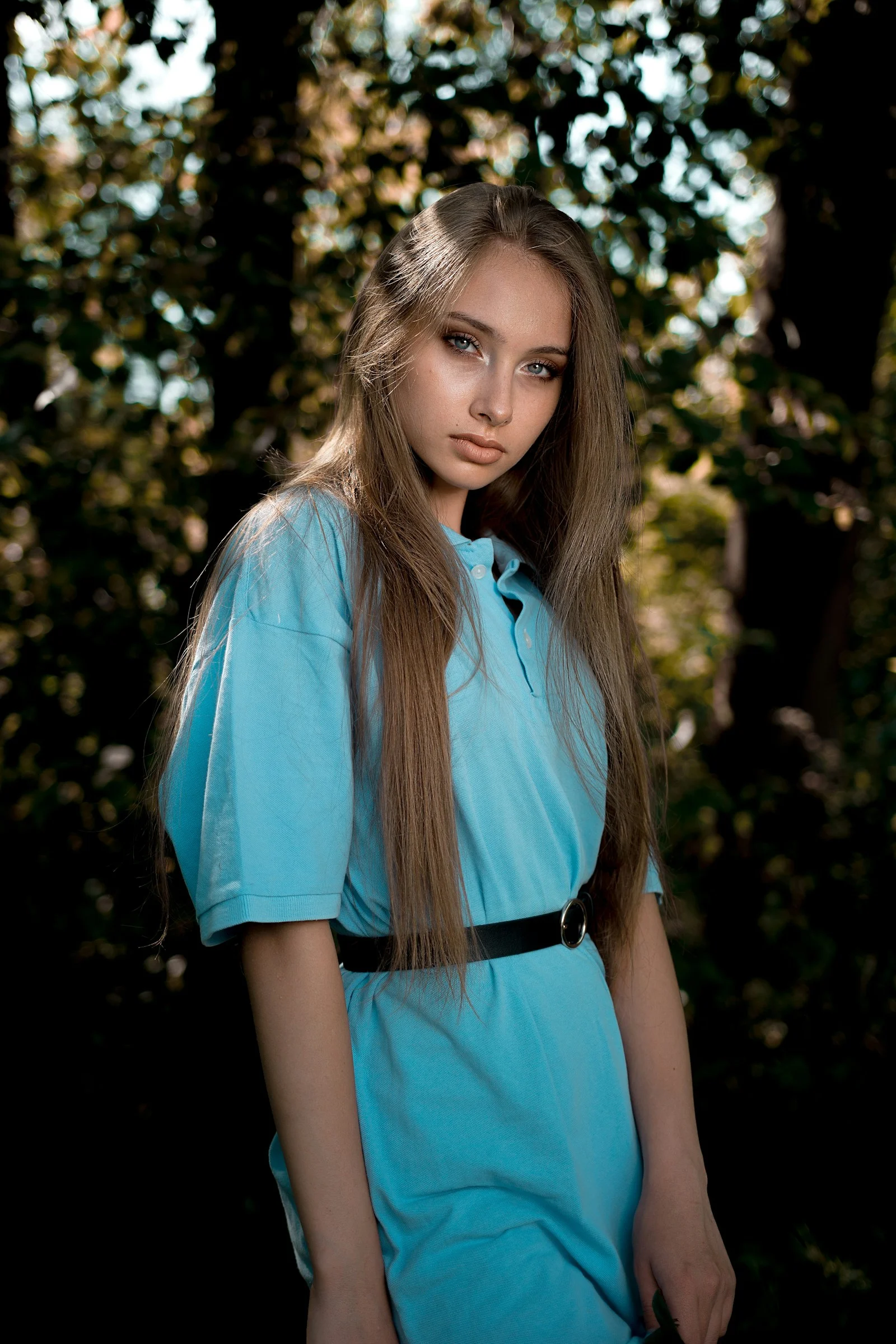 a woman with long hair standing in front of trees