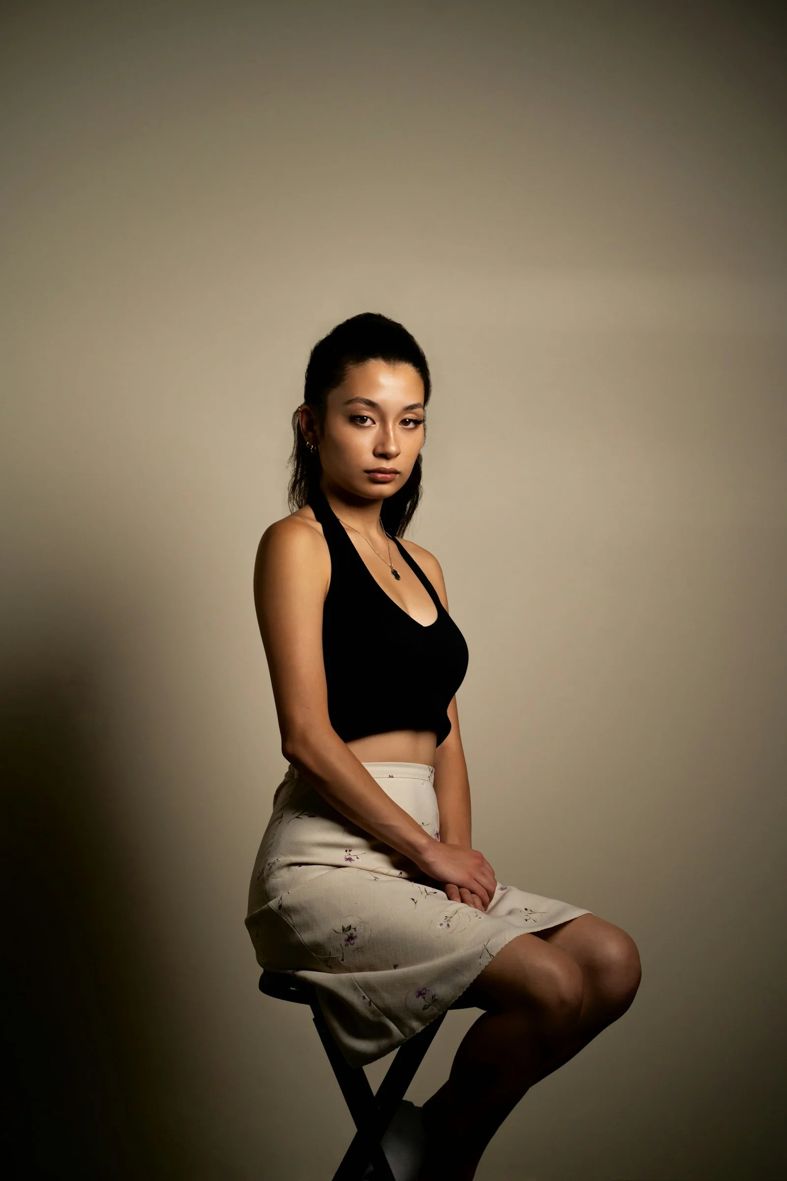 身穿黑色背心與白色長褲的女子坐在白色織物上