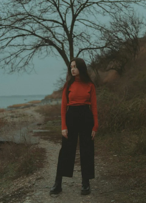 一位站在树旁土路上的女性