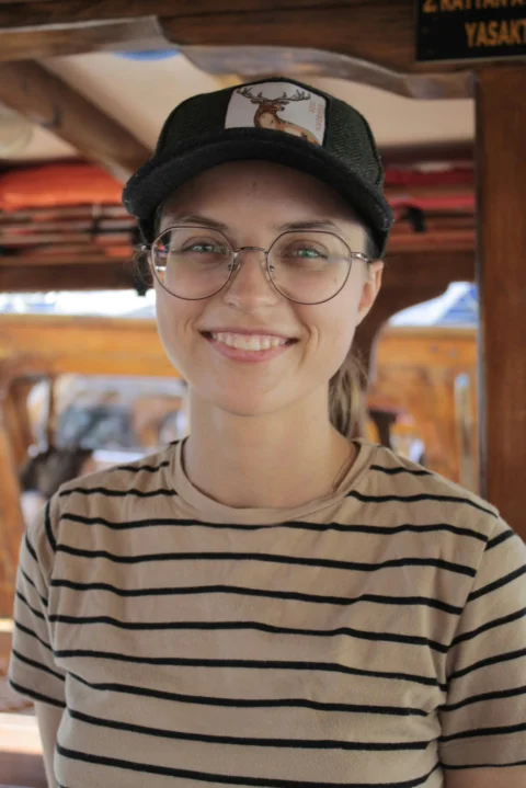 A woman wearing glasses and a hat smiling