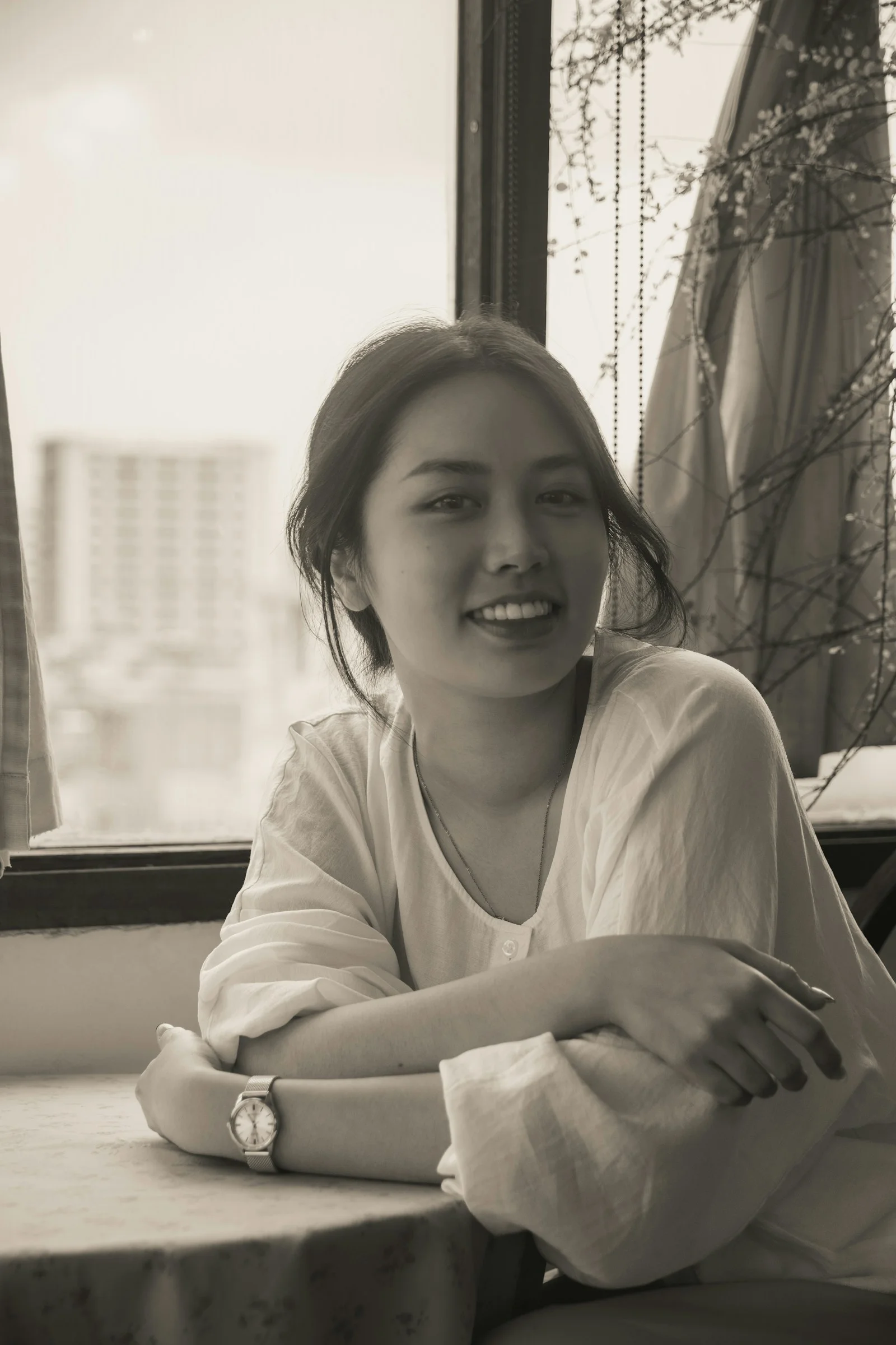 穿白衬衫的微笑女人坐在窗边的桌旁