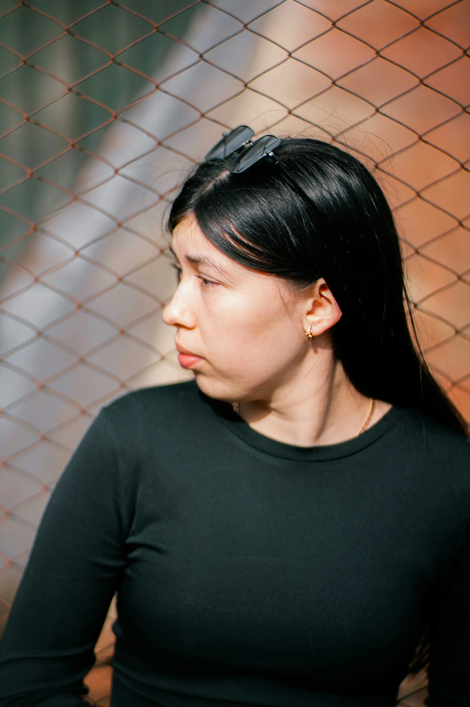 Woman looks away, resting against a fence