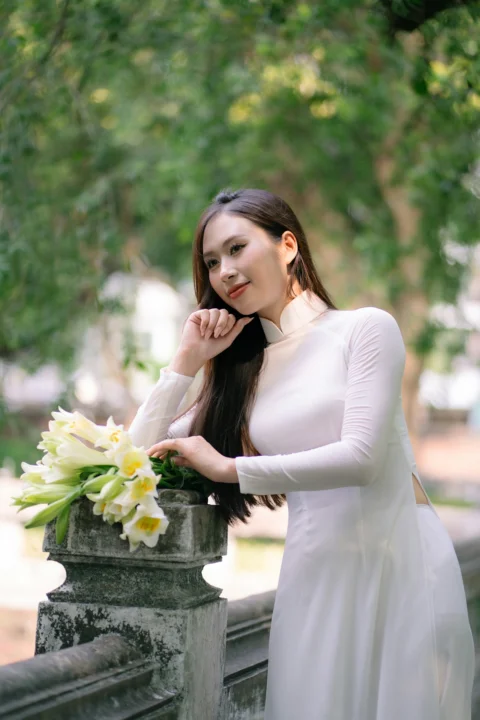 穿白色连衣裙的女子优雅地拿着花摆姿势