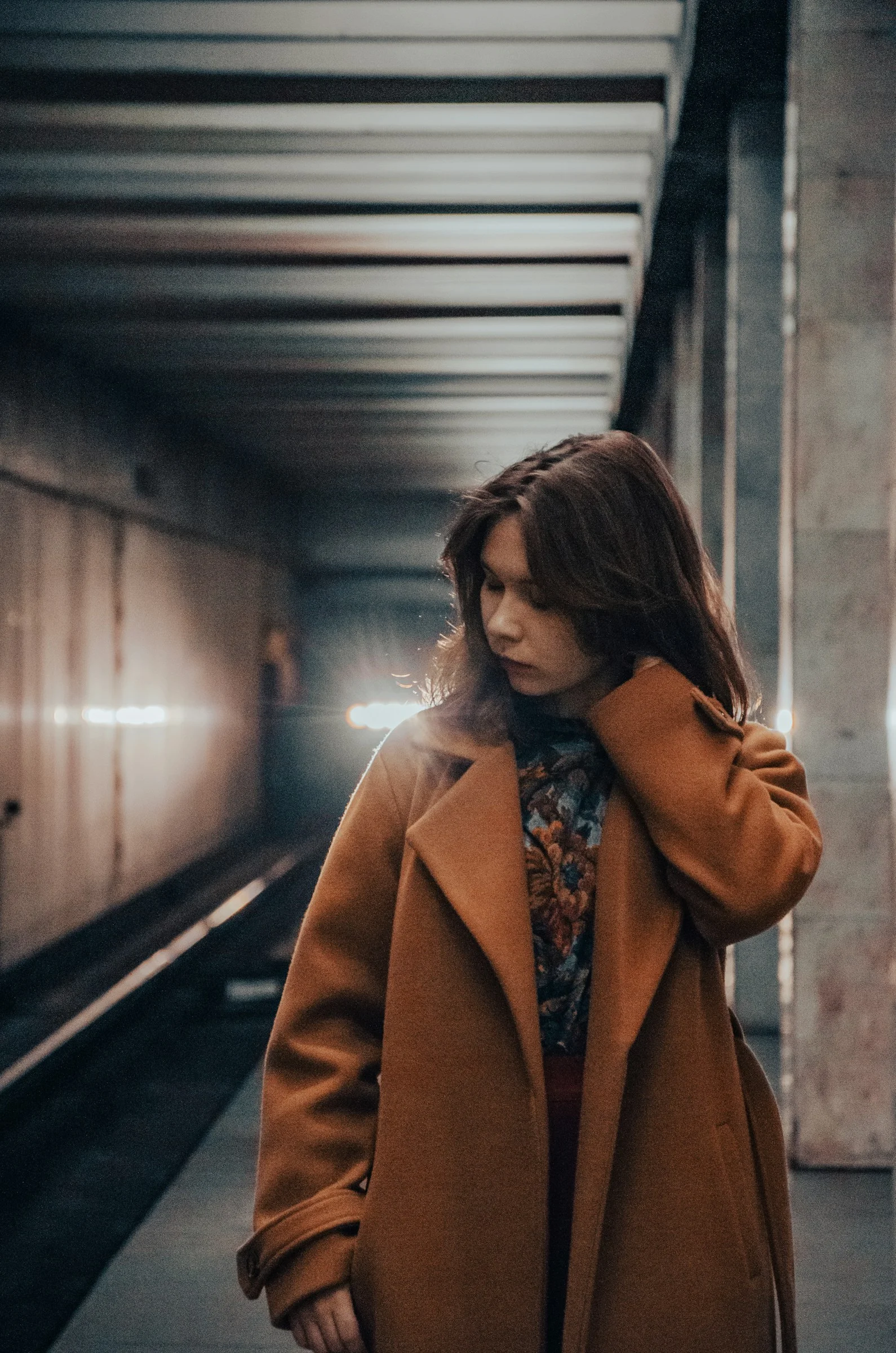 一位女性站在地铁站里，手放在头上