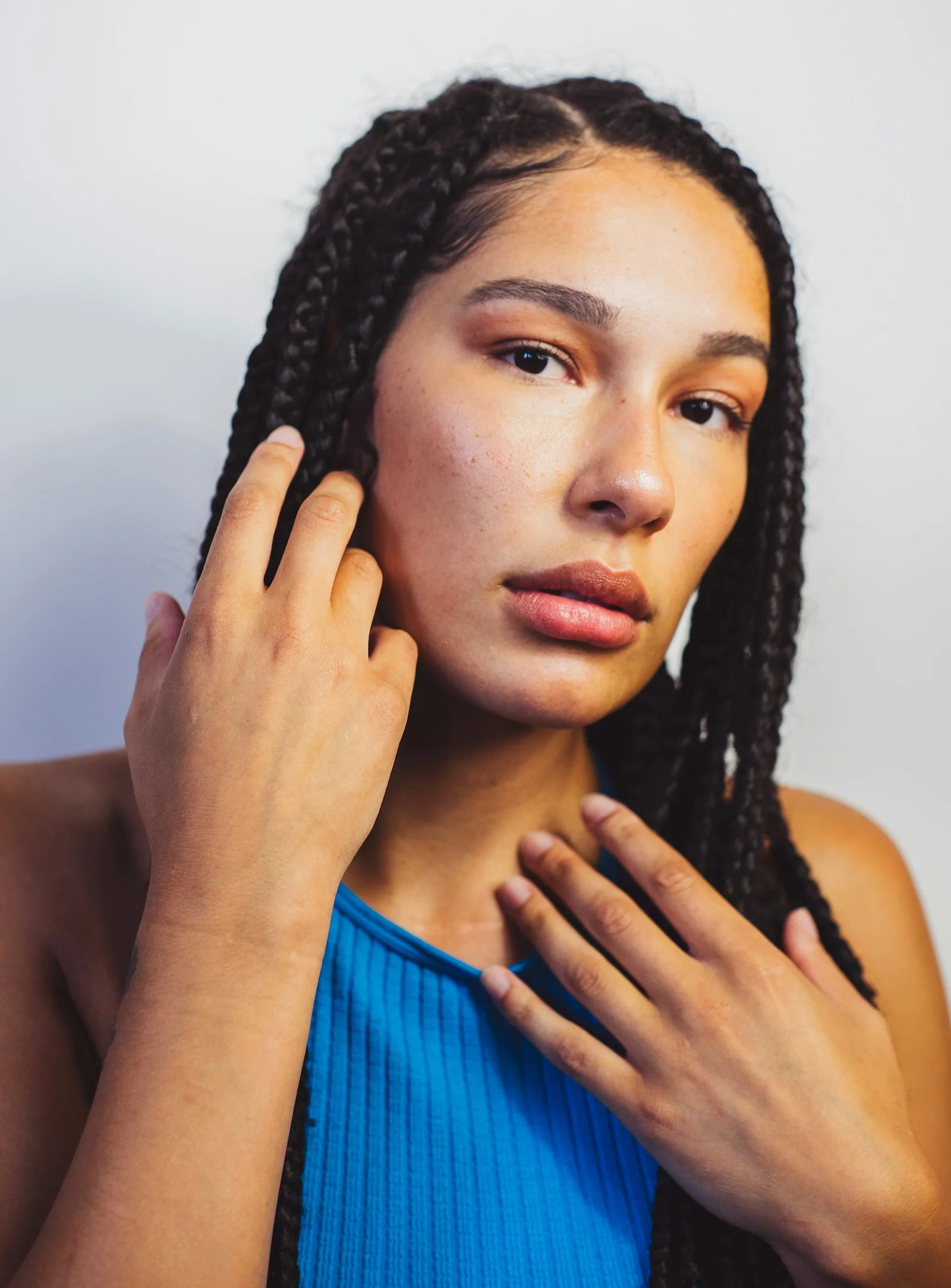 a woman with braids holding her hand up to her face